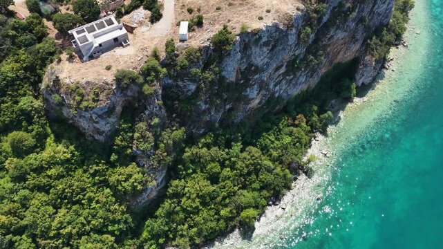 Aerial drone view of Trpejca village on Lake Ohrid, North Macedonia, traditional buildings, crystal clear turquoise lake water, rocky shoreline and beautiful lakeside beach.