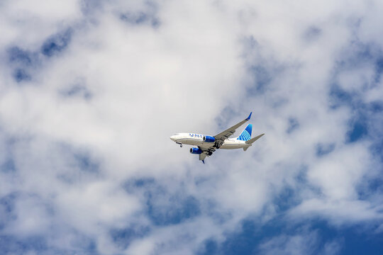 Tustin, CA, USA - August 7, 2026: A United Airlines airplane in flight with landing gears out against a blue cloudy sky coming in for a landing.