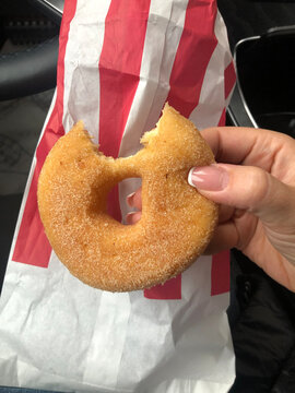 Bitten doughnut and paper bag. eating in a car. Fast food concept