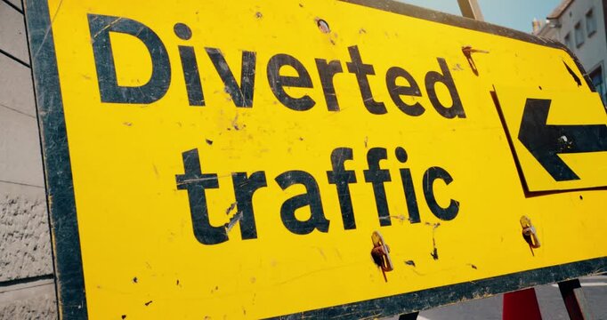 Road closed - Diverted traffic highway road sign in the event of a roadblock. Travel safety on closed street with arrow on yellow high visibility signage marking temporary closure.