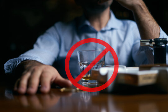 Man sitting at table with alcohol glass and cigarette, red prohibition sign symbolizing no smoking or drinking