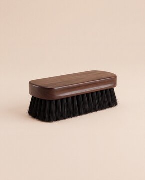 A wooden shoe brush with dense black bristles resting on a neutral light beige studio background.