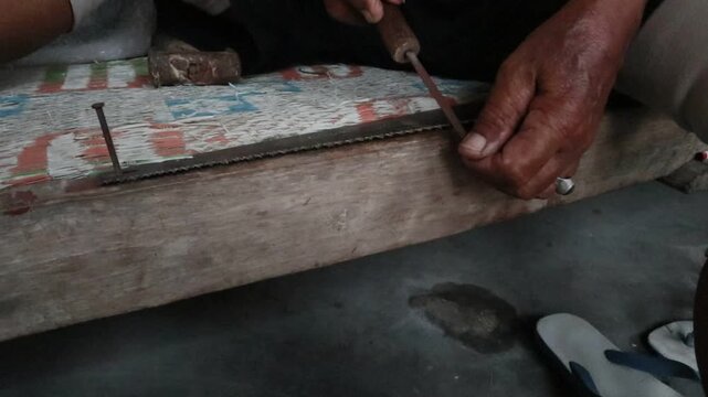 Hand sharpening a saw blade with a file to restore and improve the cutting edges of its teeth, traditional manual tool maintenance and repair.