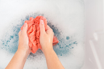 Fototapeta premium Female hands washing color clothes in sink