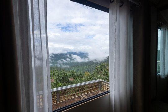 Mountain landscape window view sheer curtain balcony railing cloud forest tropical mountain misty valley outdoor scenery scenic view through window overlooking misty mountain landscape and green