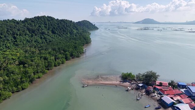 Aerial view captures lush green hills meeting a calm river at Pulau Aman