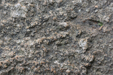 Fototapeta premium Rough stone surface with weathered gray texture and scattered mineral fragments
