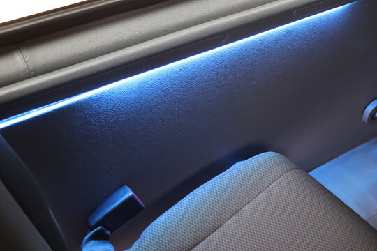 Car interior with blue ambient lighting, textured door panel and fabric seat creating modern travel atmosphere