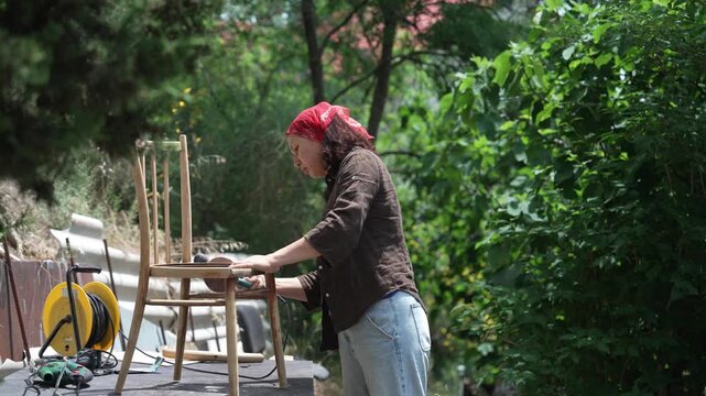 Furniture Restoration Process: Woman Sanding an Old Chair for Eco-Friendly DIY Renovation