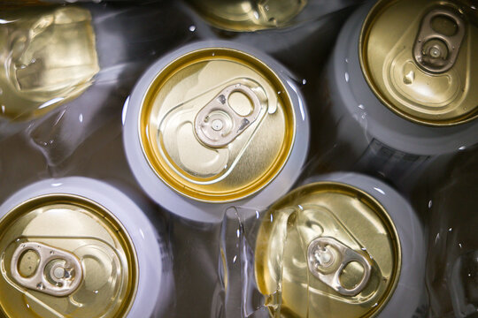 Aluminum beverage can top with pull tab surrounded by ice, close up view