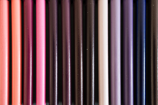 close-up of pink purple and violet colored pencils neatly lined up in pencil case, concept of creativity, drawing, education and art supplies