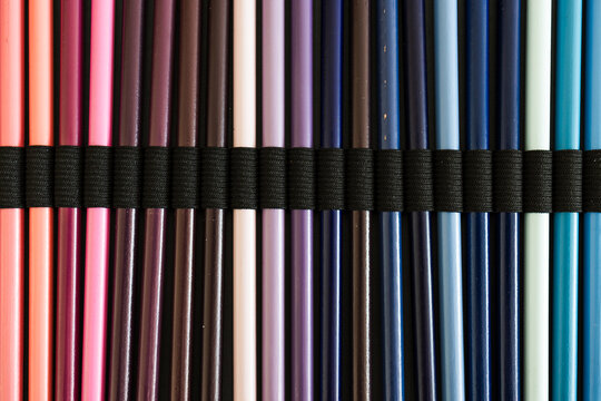 close-up of pink purple and blue colored pencils neatly lined up in pencil case, concept of creativity, drawing, education and art supplies