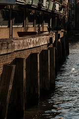 Fototapeta premium Wooden river embankment with brick wall and buildings