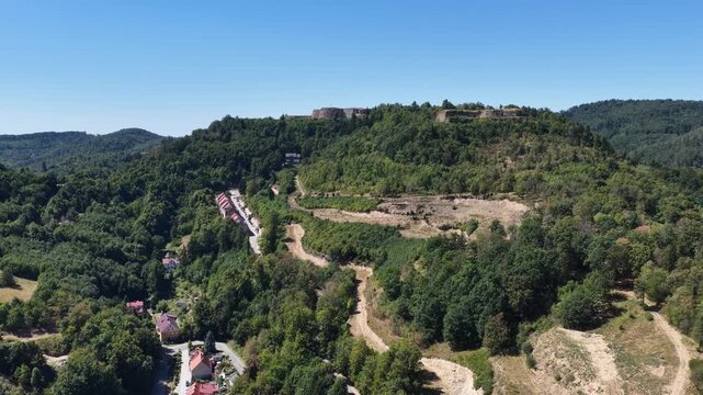 Aerial drone view of Srebrna Gora village in Lower Silesia, Poland, with historic Srebrna Gora Fortress, surrounding mountains and green landscape on a sunny summer day