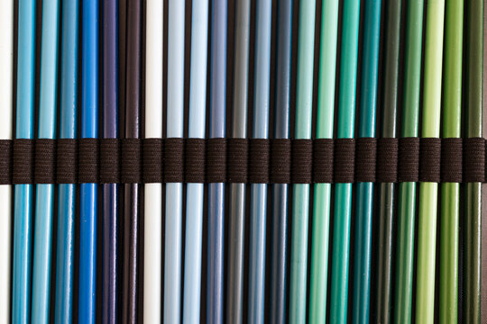 close-up of blue turquoise and green colored pencils neatly lined up in pencil case, concept of creativity, drawing, education and art supplies