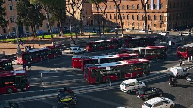 Bustling city bus terminal during morning rush hour in Rome with vehicles maneuvering through busy intersection and traffic flow.