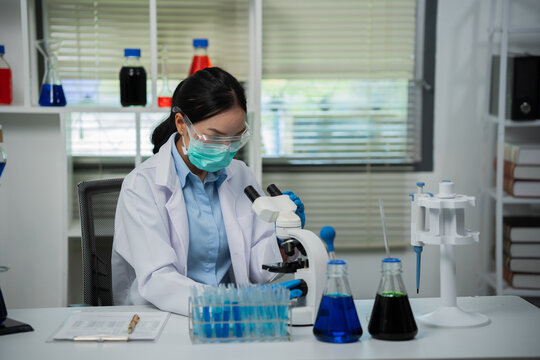A female scientist is conducting chemical research in a laboratory, analyzing samples using test tubes and a microscope to drive advancements in biotechnology, medicine, microbiology, and healthcare.
