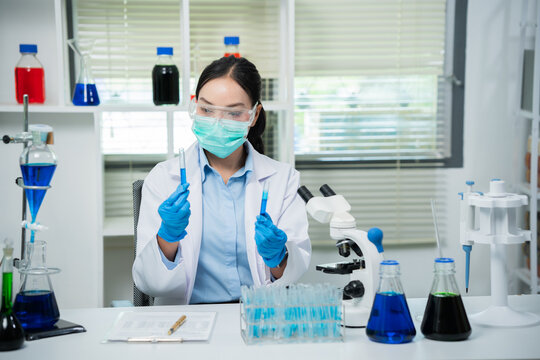 A female scientist is conducting chemical research in a laboratory, analyzing samples using test tubes and a microscope to drive advancements in biotechnology, medicine, microbiology, and healthcare.