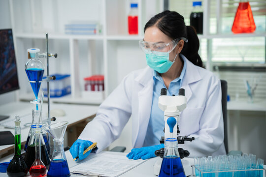 A female scientist is conducting chemical research in a laboratory, analyzing samples using test tubes and a microscope to drive advancements in biotechnology, medicine, microbiology, and healthcare.