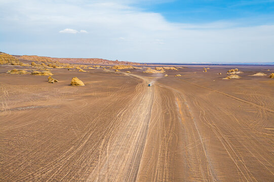 High angle view of off-road vehicle driving on dirt track in Dahaidao yardang desert landscape, Xinjiang, China.