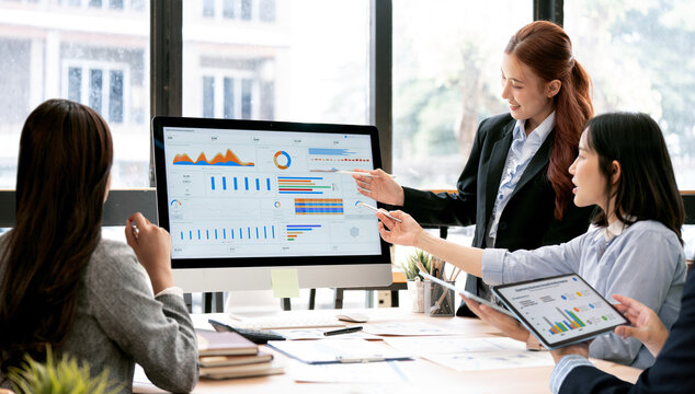 Asian Business Team Pointing Pens at Computer Screen Analyzing Dashboard in Office