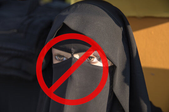 Mannequin wearing muslim traditional black clothing with stop sign. Concept of ban of traditional islamic clothes hijab, niqab, chador, burqa dress