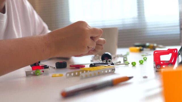 Close up of child hands assembling 3D printed robot model on table. Concept of STEM education, robotics learning, creativity, and technology development