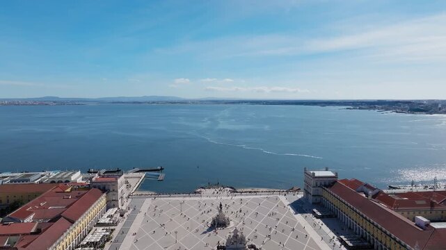 Stunning drone video captures Praca do Comercio and the Rua Augusta Arch with vibrant activity, vivid architecture and blue Tagus River under clear daylight, with a lot of tourists visiting the square
