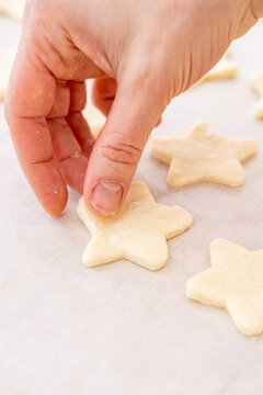 Preparing cookies. Pastry culinary. Woman baker hand placing star cut treat raw dough on white paper sheet making traditional sweets.