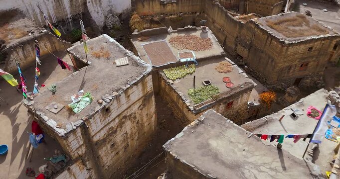 Annapurna Circuit, Mustang Nepal, drone pulls out from traditional mud-brick houses with colorful crops and spices drying on flat rooftops in a Himalayan desert village