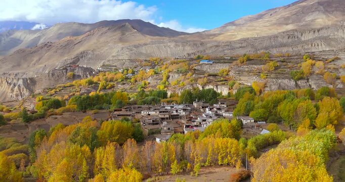 Annapurna Circuit, Mustang Nepal: drone orbits around a traditional remote village framed by bright autumn foliage and expansive Himalayan desert landscapes.