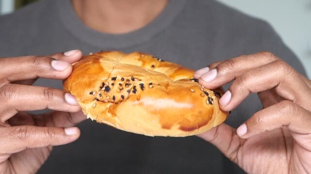 Holding a bagel with sesame seeds in a kitchen