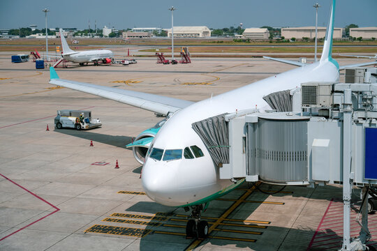 Passengers prepare to board the vibrant airplane at the bustling airport, while a second jet awaits in the background under a clear blue sky