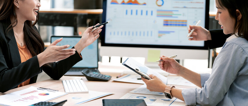 Asian Business Women Discussing Financial Data and Reports in Modern Office