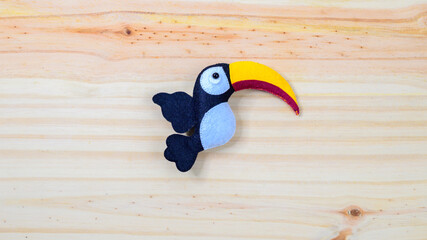 Cute handmade toucan bird on a wooden background with copy space © nilanka