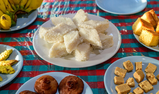 Traditional Sinhala Aluth Avurudu food table featuring kiribath, Sri Lankan sweets, cakes, bananas, and homemade treats arranged on plates, celebrating the Sri Lankan New Year cultural tradition
