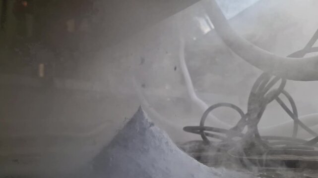 Cryogenic liquid nitrogen release with dry ice sublimation and dense white vapor near industrial machine parts