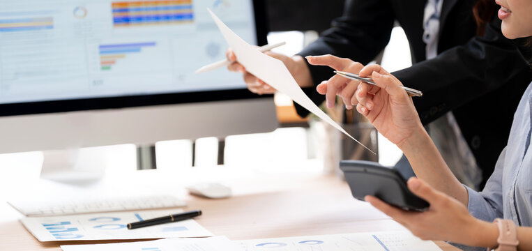 Asian Business Women Pointing Pens at Paper Report and Calculator in Office