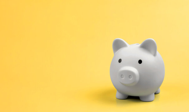 White minimalist piggy bank on vibrant yellow background with copy space. Concept of money saving, financial planning, investment, and wealth management.