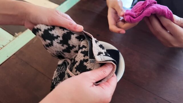Asian Hands Folding and Preparing Cleaning Towels at a Restaurant Table