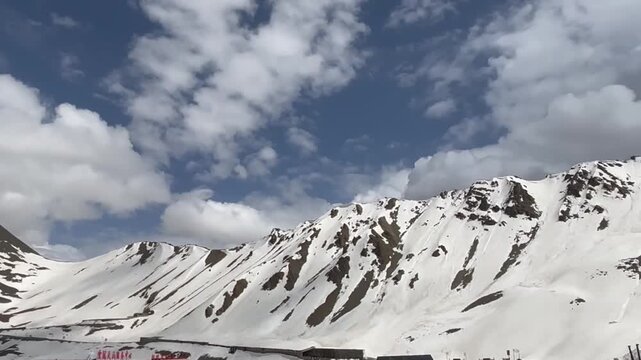 A quiet rest stop sits below a towering snow‑covered peak along Xinjiang&rsquo;s high‑altitude Duku Highway.