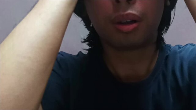 Close up of young Asian man messing up long black hair indoor