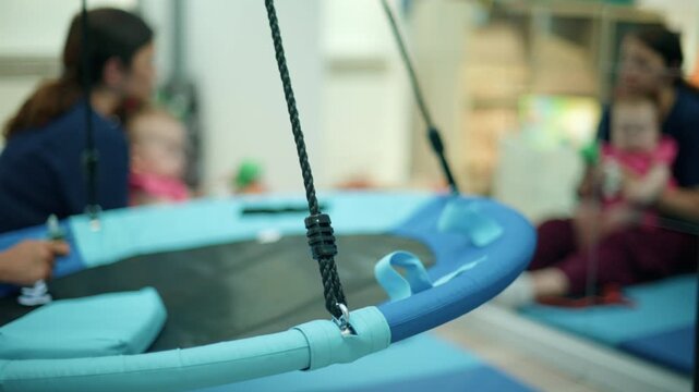 Child receiving sensory integration therapy, swinging on a platform swing with an occupational therapist providing support