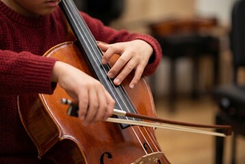 Fototapeta premium Young Student Playing Cello Focusing on Precise Finger Placement and Bow Technique