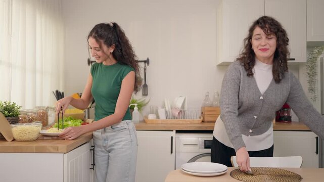 Senior Latino mother and young adult daughter setting the dining table. 