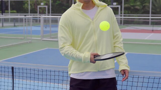 Close up of male pickleball player balance pickleball on paddle on outdoor court.