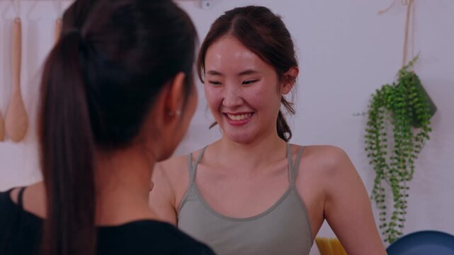 Asian woman mirror smile reflection bathroom home ponytail tank top cheerful self care routine near tile wall hanging plant indoor portrait happy lifestyle casual scene
