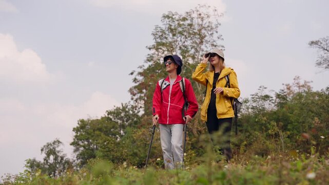 Caucasian hikers with backpacks using binoculars on a mountain trail. 