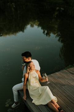 Couple sitting by the water holding drinks while enjoying the evening sunlight