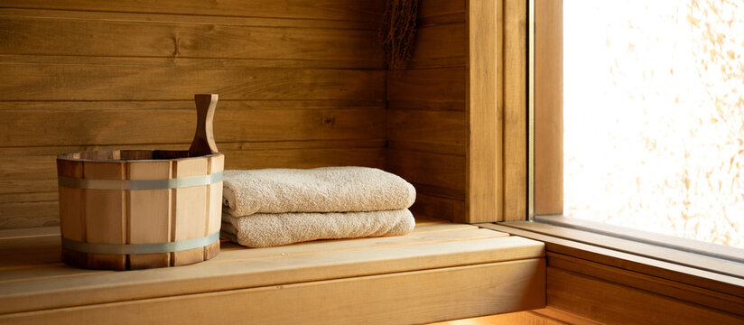 Wooden sauna interior features neatly folded towels and a wooden bucket